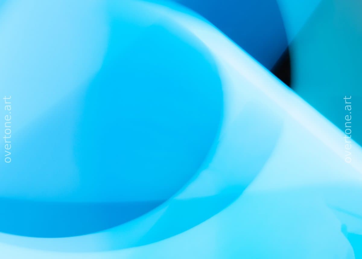 Smooth, softly glowing curved forms in cyan, turquoise, and deep blue overlap and swirl across an out-of-focus abstract composition.